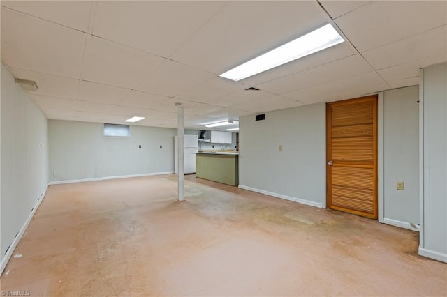 basement with a paneled ceiling and white fridge