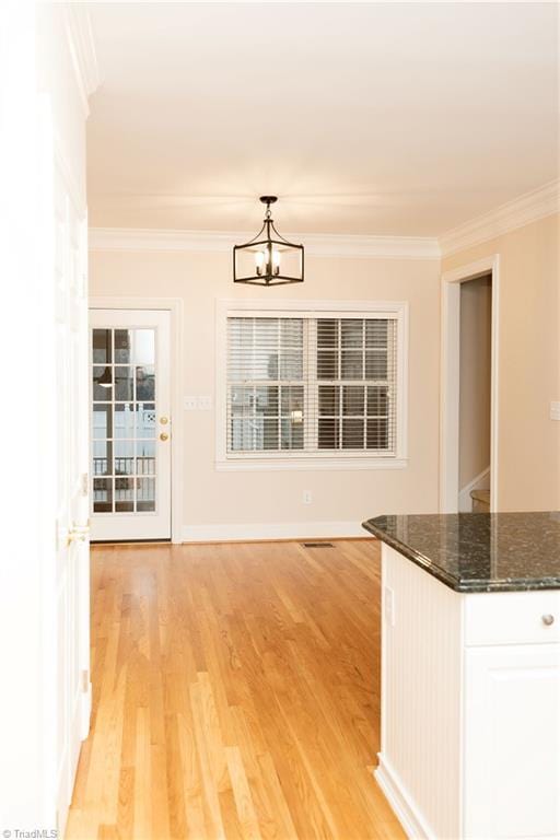 unfurnished dining area with an inviting chandelier, light hardwood / wood-style flooring, and crown molding