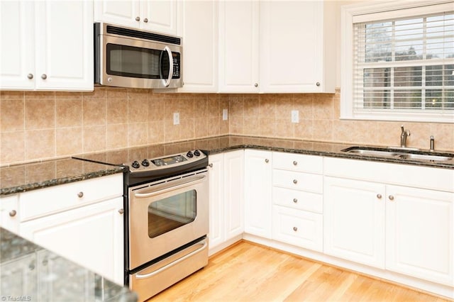 kitchen with dark stone countertops, light hardwood / wood-style flooring, white cabinets, and stainless steel appliances