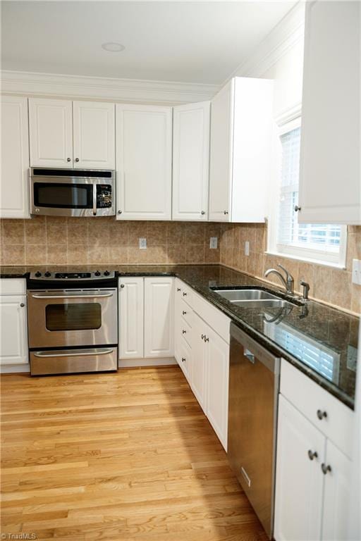 kitchen with ornamental molding, stainless steel appliances, sink, white cabinets, and light hardwood / wood-style floors