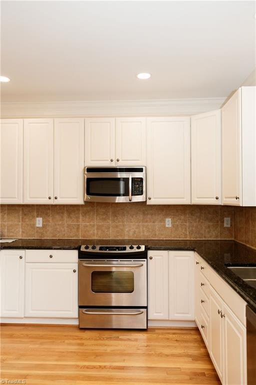 kitchen featuring decorative backsplash, stainless steel appliances, white cabinetry, and light hardwood / wood-style floors