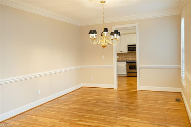 unfurnished dining area featuring light hardwood / wood-style floors, crown molding, and an inviting chandelier