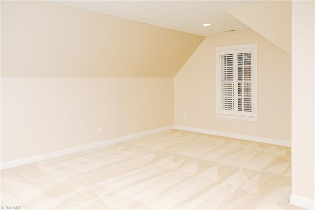 additional living space featuring light carpet and vaulted ceiling