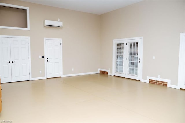 unfurnished room featuring a towering ceiling and a wall unit AC