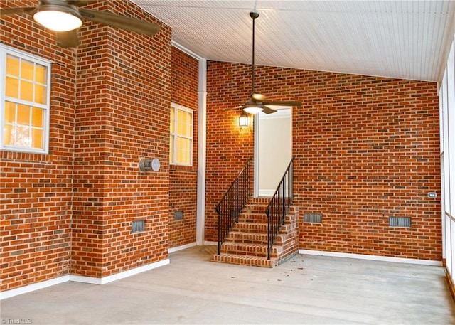 interior space featuring concrete flooring, lofted ceiling, and brick wall