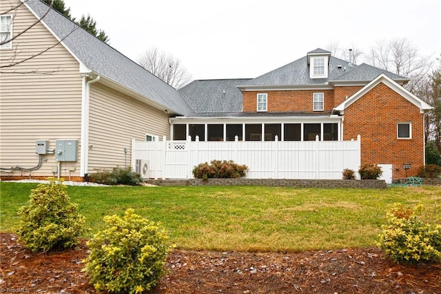 back of property featuring a sunroom, ac unit, and a lawn