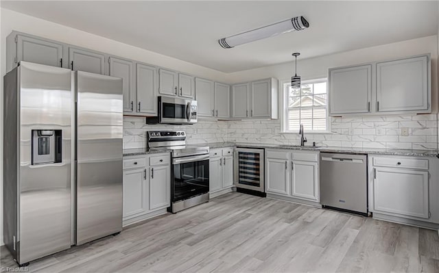 kitchen with stainless steel appliances, sink, pendant lighting, light hardwood / wood-style floors, and wine cooler