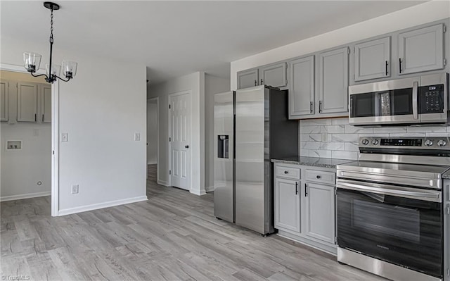 kitchen featuring decorative backsplash, appliances with stainless steel finishes, light hardwood / wood-style flooring, a notable chandelier, and gray cabinets