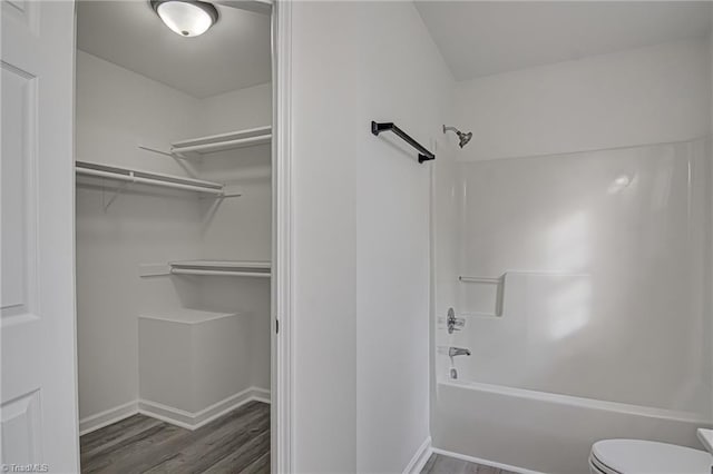 bathroom featuring hardwood / wood-style flooring, shower / bathtub combination, and toilet