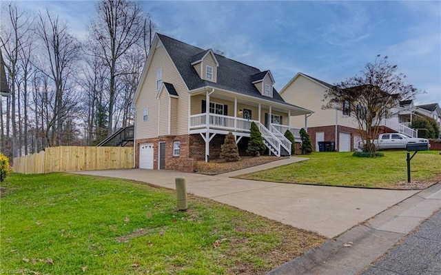 view of front of home featuring covered porch, a garage, and a front yard