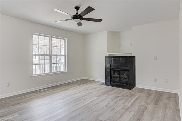 unfurnished living room featuring ceiling fan, a fireplace, and light hardwood / wood-style floors