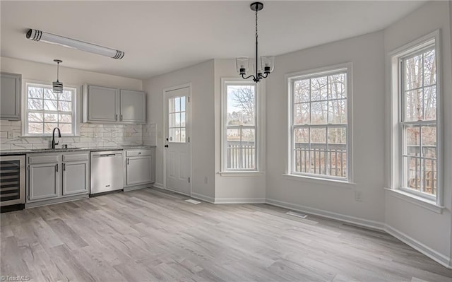 kitchen with stainless steel dishwasher, beverage cooler, a wealth of natural light, and pendant lighting