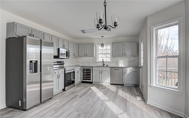 kitchen with sink, hanging light fixtures, an inviting chandelier, wine cooler, and appliances with stainless steel finishes