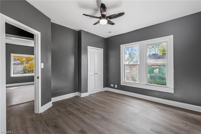 unfurnished bedroom featuring dark wood-type flooring, ceiling fan, and a closet