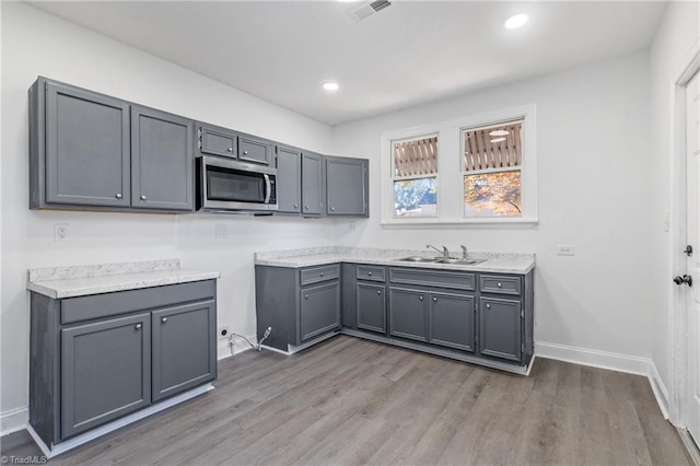 kitchen with gray cabinets, sink, and wood-type flooring