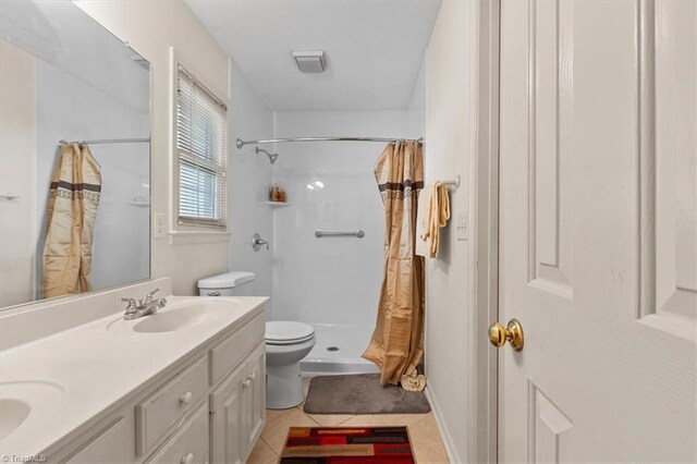 bathroom featuring tile patterned floors, double vanity, a shower with shower curtain, toilet, and a sink