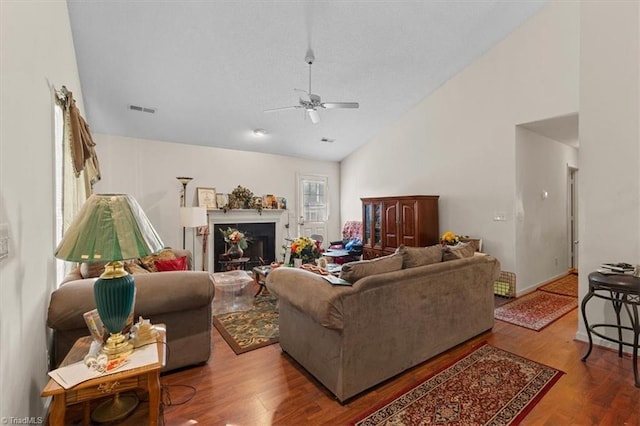 living area with visible vents, ceiling fan, a fireplace, wood finished floors, and high vaulted ceiling