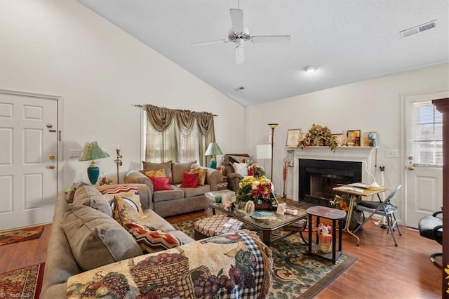 living room featuring a ceiling fan, visible vents, wood finished floors, and a fireplace