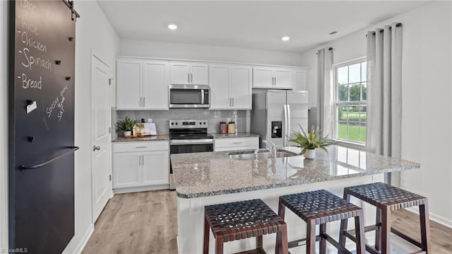 kitchen with a breakfast bar, appliances with stainless steel finishes, and white cabinetry