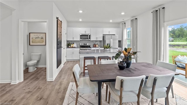 dining space featuring a barn door and light hardwood / wood-style flooring