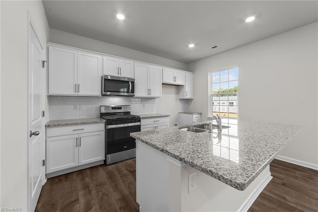 kitchen with a kitchen island with sink, dark wood-type flooring, sink, white cabinetry, and stainless steel appliances