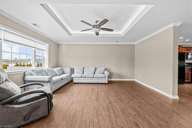 living room with crown molding, a tray ceiling, ceiling fan, and hardwood / wood-style flooring