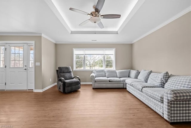 living room featuring ceiling fan, ornamental molding, wood-type flooring, and a raised ceiling