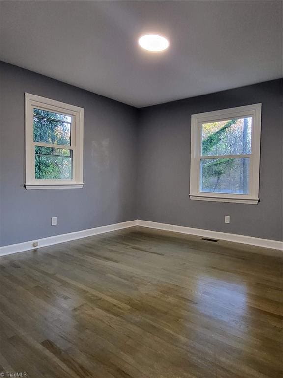 spare room with plenty of natural light and dark hardwood / wood-style floors