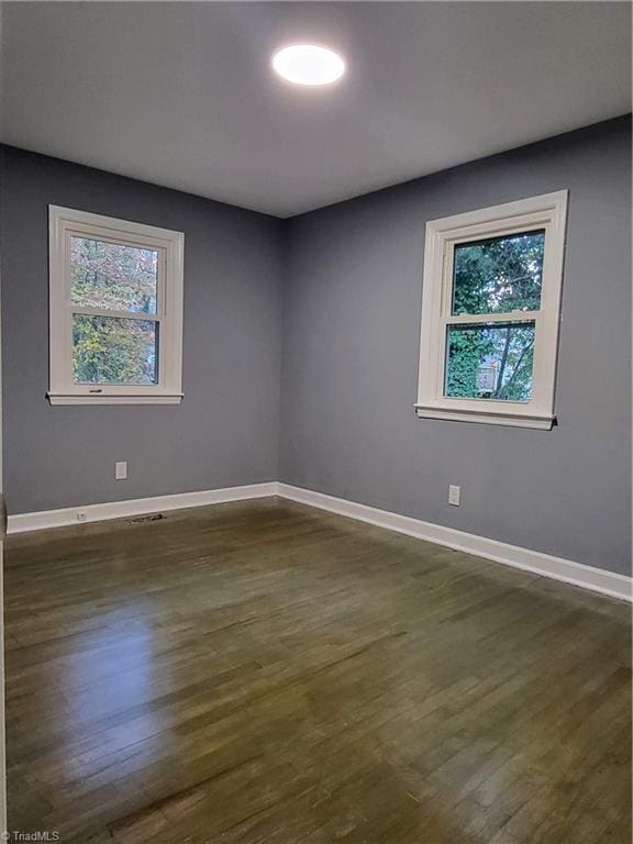 spare room with dark wood-type flooring and a healthy amount of sunlight