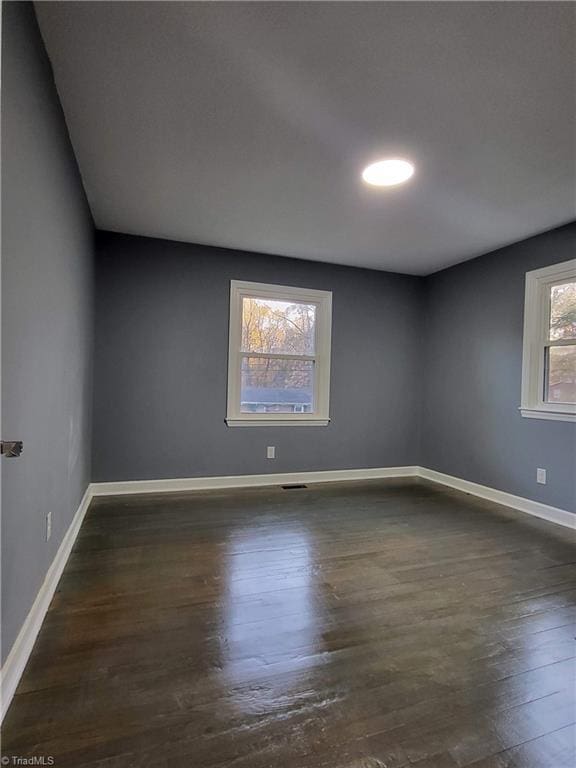 unfurnished room with dark hardwood / wood-style flooring and a healthy amount of sunlight