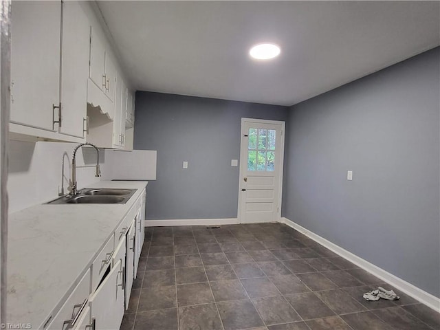 kitchen with white cabinetry, dark tile patterned floors, and sink