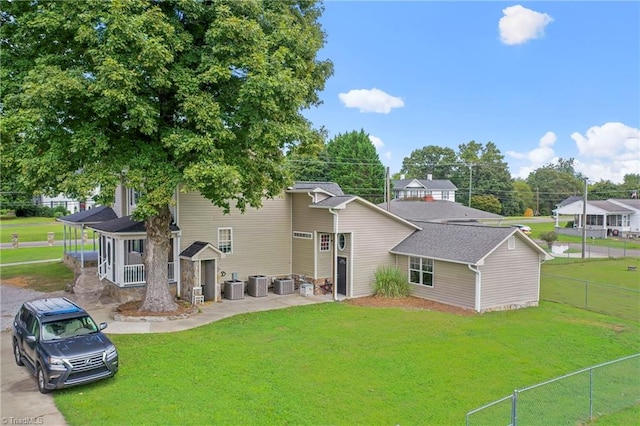 rear view of house featuring covered porch, central AC unit, and a lawn