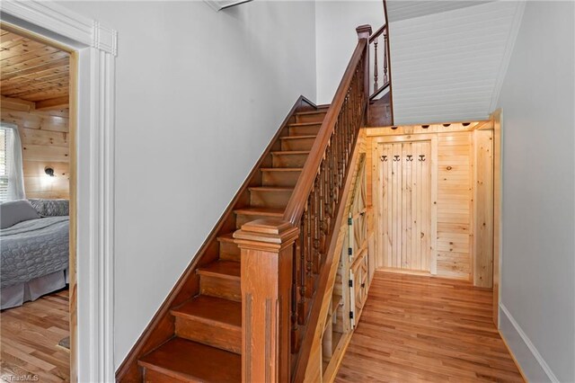 stairway with wooden ceiling, hardwood / wood-style floors, and wood walls