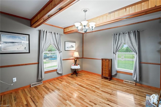 empty room with ornamental molding, beamed ceiling, light hardwood / wood-style flooring, and a chandelier