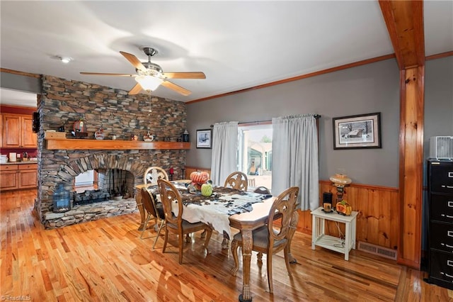 dining room with a fireplace, crown molding, light hardwood / wood-style flooring, and ceiling fan