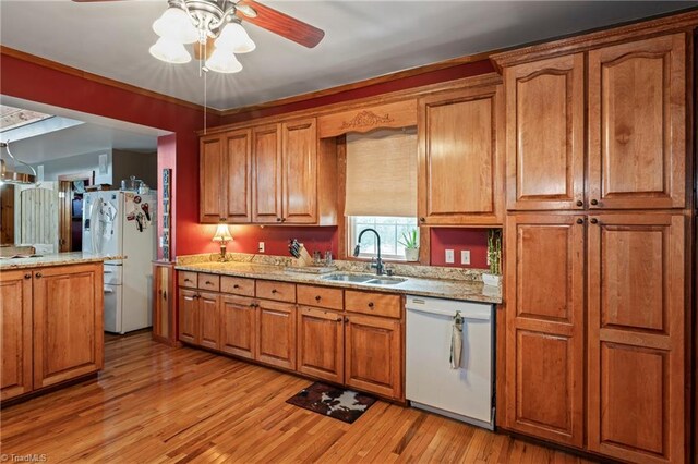 kitchen featuring light wood-type flooring, white appliances, light stone counters, sink, and ceiling fan