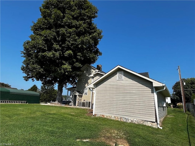 view of side of property with a lawn and central AC