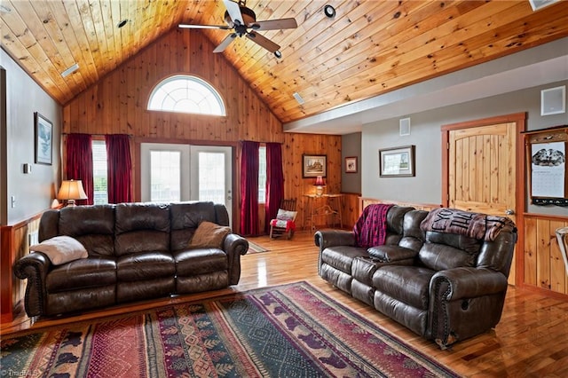 living room featuring high vaulted ceiling, light hardwood / wood-style flooring, wood walls, ceiling fan, and wood ceiling