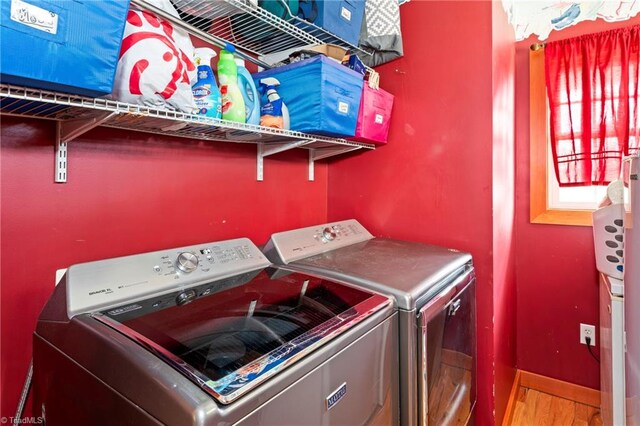 laundry room with light hardwood / wood-style flooring and washing machine and clothes dryer