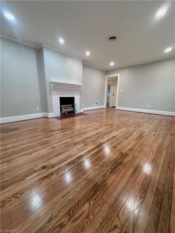1214 Fillman Dr, Reidsville, NC 27320 - unfurnished living room featuring visible vents, baseboards, crown molding, and hardwood / wood-style flooring