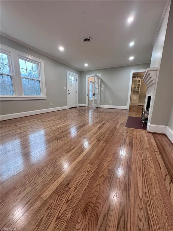 1214 Fillman Dr, Reidsville, NC 27320 - unfurnished living room with visible vents, a brick fireplace, baseboards, and wood finished floors