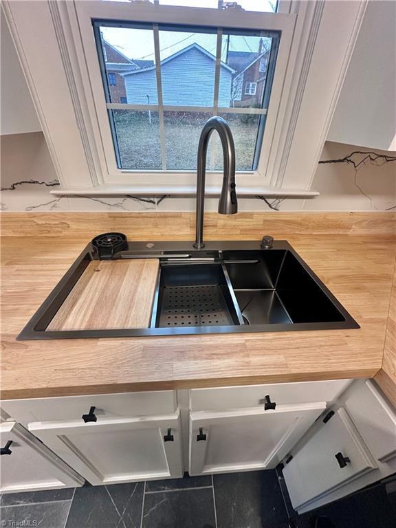 1214 Fillman Dr, Reidsville, NC 27320 - room details featuring white cabinetry, wooden counters, and a sink