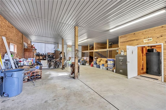 misc room with unfinished concrete floors, wood walls, and a garage
