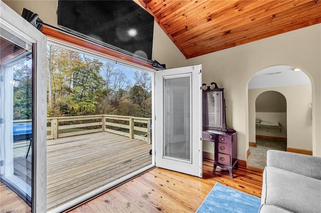 interior space with arched walkways, vaulted ceiling, and wood finished floors