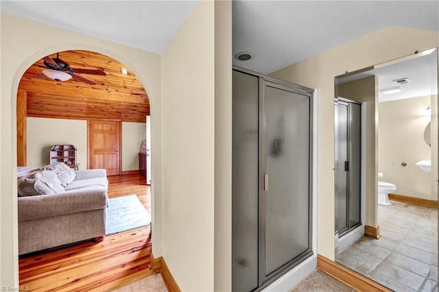 ensuite bathroom with lofted ceiling, toilet, a shower stall, a ceiling fan, and ensuite bath