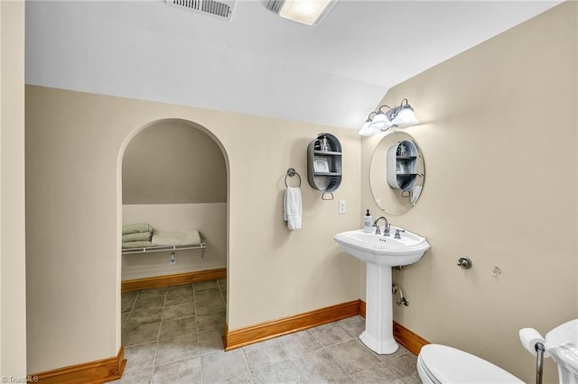 half bath featuring visible vents, tile patterned flooring, vaulted ceiling, baseboards, and toilet