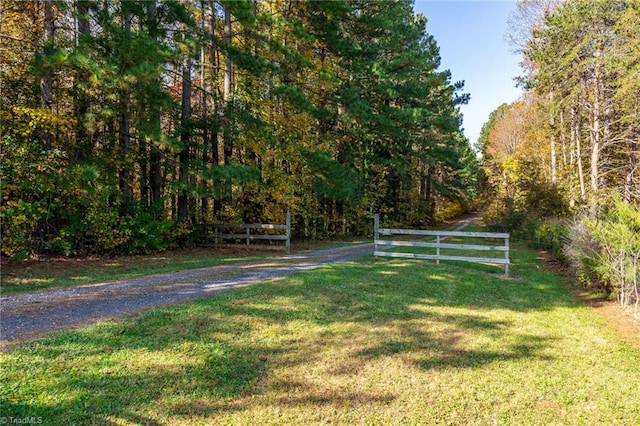 exterior space with fence, a view of trees, and a lawn