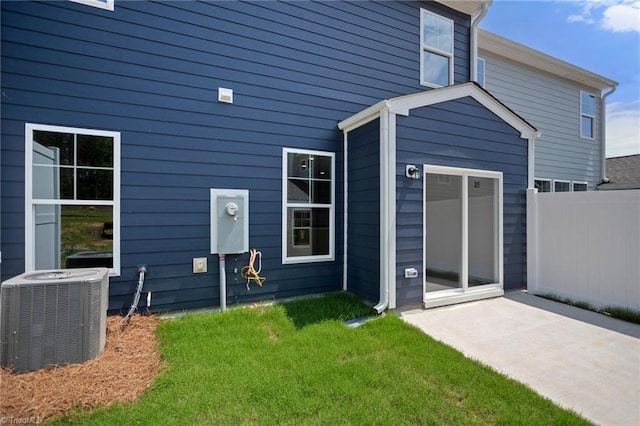 rear view of house with a lawn, central AC, and a patio