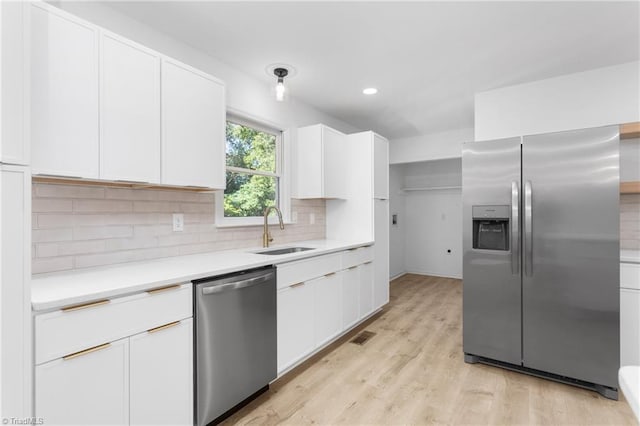 2282 Valewood Dr, Asheboro, NC 27205 - kitchen with appliances with stainless steel finishes, light countertops, white cabinets, backsplash, and light wood-style flooring
