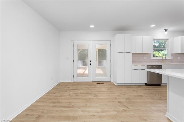 2282 Valewood Dr, Asheboro, NC 27205 - kitchen with stainless steel dishwasher, french doors, light countertops, white cabinets, and decorative backsplash